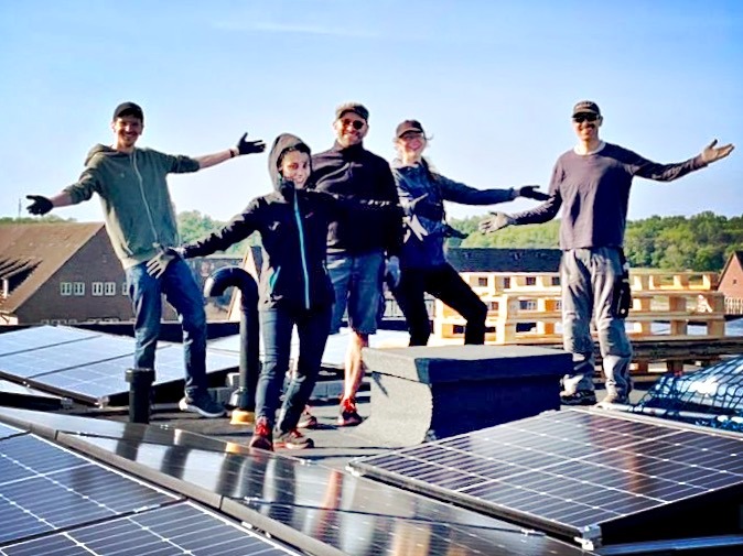 Mitglieder der Genossenschaft präsentieren auf dem Dach die installierte PV-Anlage