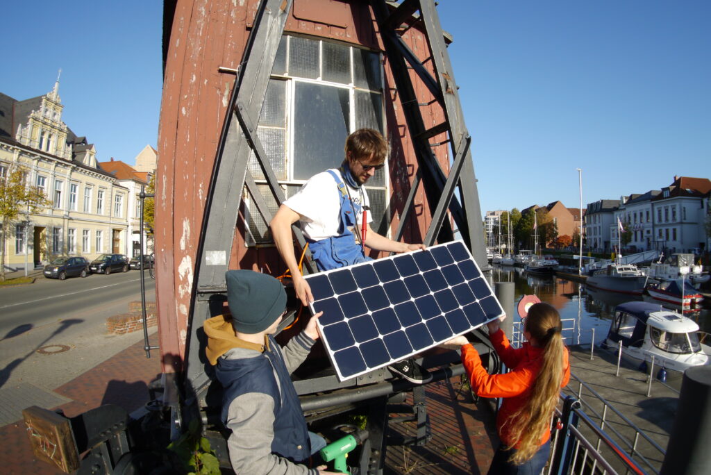Menschen betrachten ein PV-Modul am Stau in Oldenburg.