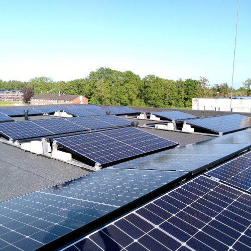 Foto vom Dach eines Mehrfamilienhauses mit verteilten Solarmodulen.
