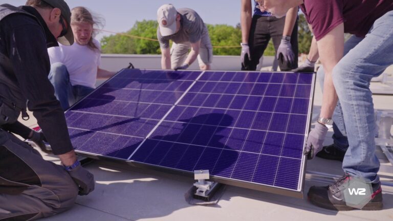 Mitglieder der Olegeno installieren ein Solarmodul.